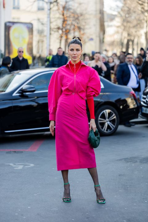 vrouw poseert in roze jurk met rode top eronder tijdens paris fashion week