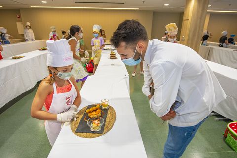una niña cocina un plato frente a un chef