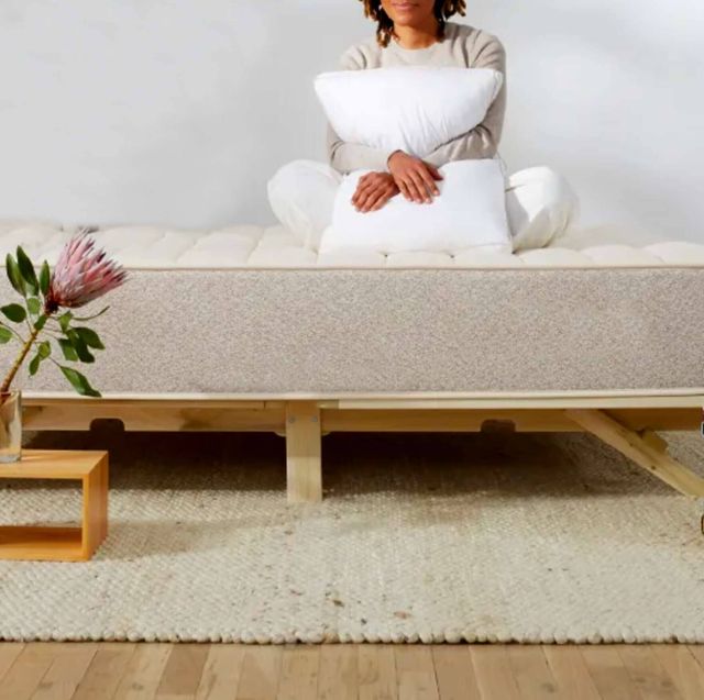 person sitting on a mattress and holding a pillow