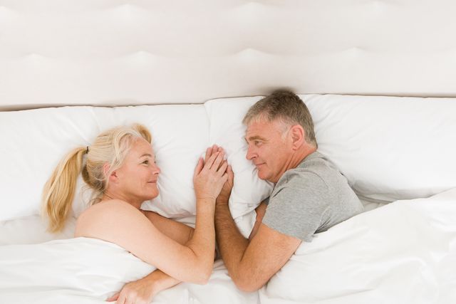 mature couple holding hands in bed
