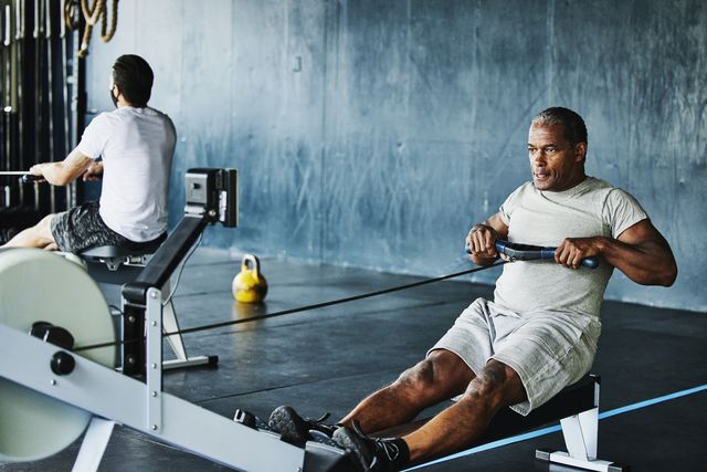mature man working out on rowing machine in gym