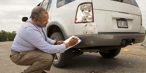 Mature man writing on clipboard by crashed car mature man writing on clipboard by crashed car
