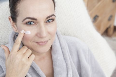 mature woman applying moisturiser to face