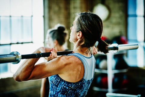 Mature woman doing barbell lifts during workout