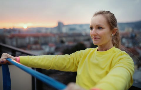 blonde woman exercises with resistance band outside