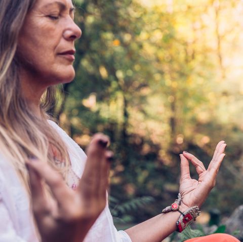 mature woman meditating in forest