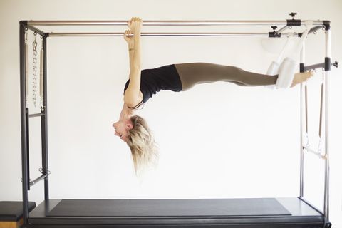 Mature woman practicing pilates on trapeze table in pilates gym