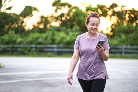 Mature woman walking at sunset carrying a mobile phone mature woman walking at sunset carrying a mobile phone