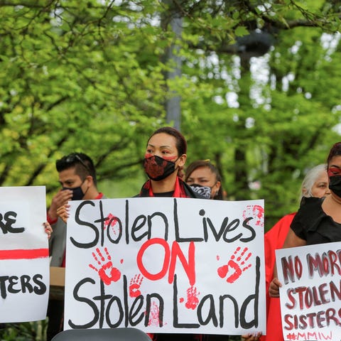 CANADA-VANCOUVER-RED DRESS DAY woman with her face painted holding a sign that says stolen lives on stolen lands