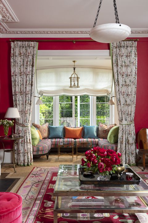 in the living room a convivial window seat overlooks an emerald and white back garden and a banquette has striped fabric
