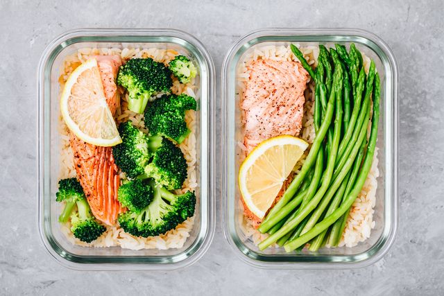 meal prep lunch box containers with baked salmon fish, rice, green broccoli and asparagus
