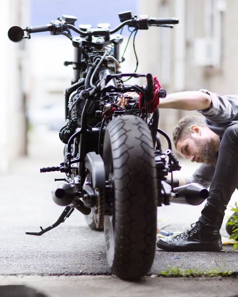 man looking at a motorcycle outside of a garage