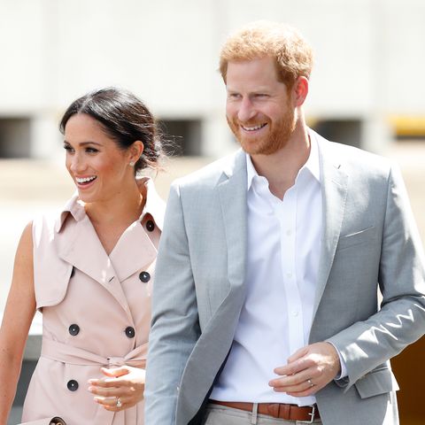 Meghan and Harry's out of office message is now officially on. Here's a photo of them smiling and walking together. Meghan is in a chic pale pink dress and Harry is in a smart suit, they look relaxed and happy. The picture is from July 2018.