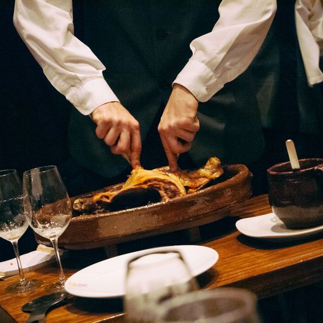 camarero despieza el típico cochinillo de segovia en un restaurante