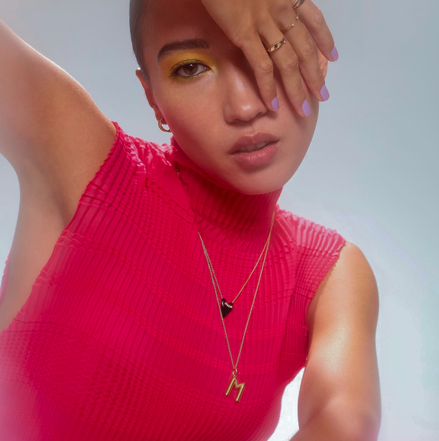 a model wears a pink mock neck sweater with two dainty necklaces