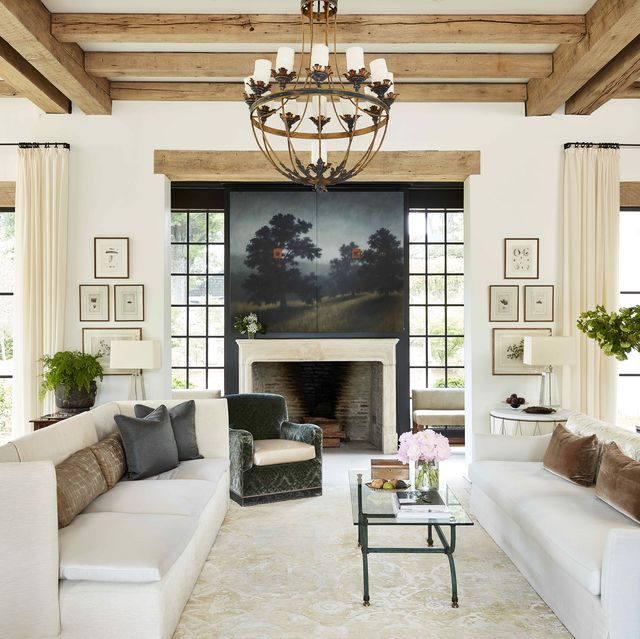 two sofas face each other in a large living space with a landscape painting hanging above the fireplace