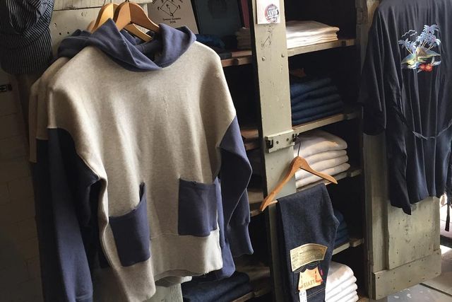 a patch pocket hoodie handing next to shelves of folded jeans