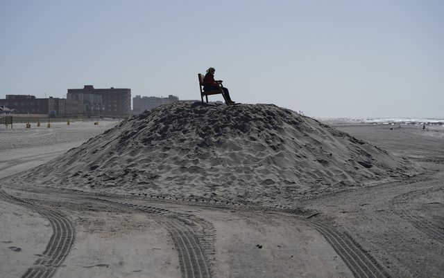 a woman sits in a empty lifeguard chair on top of a mound of sand on the beach at in long beach, new york may 22, 2020, as people get started on the memorial day weekend   the 22 mile boardwalk, which has been closed for two months amid fears of spreading covid 19, will only be available to city residents photo by timothy a clary  afp photo by timothy a claryafp via getty images