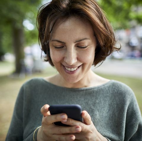 smiling woman using cell phone in a park