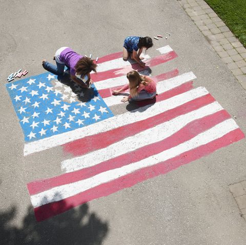 girls with chalk coloring american flag on sidewalk