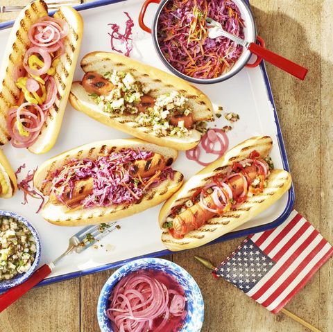 a try of grilled hot dogs with toppings and an american flag