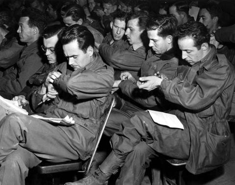 men of a us troop carrier group, 1st allied airborne army, synchronize their watches during a briefing preceeding the droping of paratroopers and gliders troops east of the rhine river