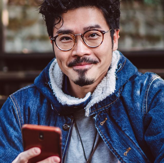 man with phone wearing glasses and jean jacket sitting on steps