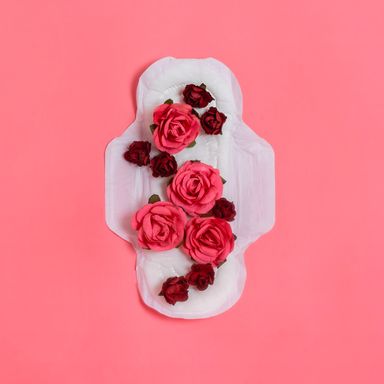white sanitary pad with red and pink flowers on it to indicate blood on a pink background