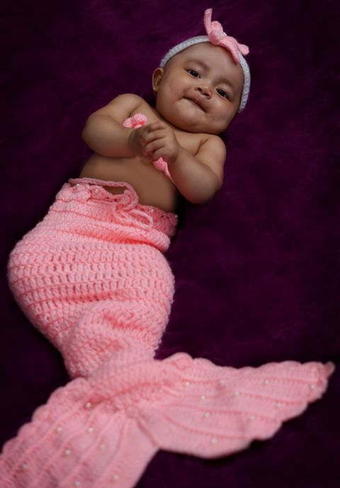 portrait of cute girl in mermaid costume that is crocheted with pink yarn