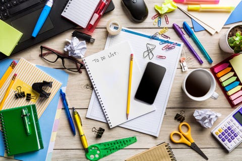 messy desktop with office supplies on rustic wooden table