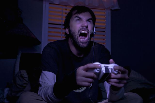 mid adult man shouting whilst playing video game at night