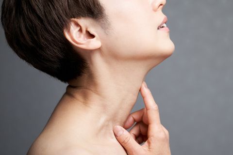middle aged japanese woman holding her neck