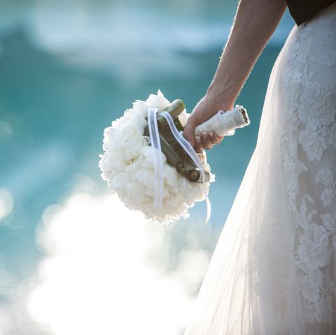 Midsection Of Bride Wearing Wedding Dress While Holding Bouquet By Swimming Pool