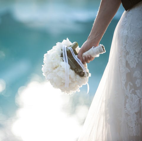 Midsection Of Bride Wearing Wedding Dress While Holding Bouquet By Swimming Pool