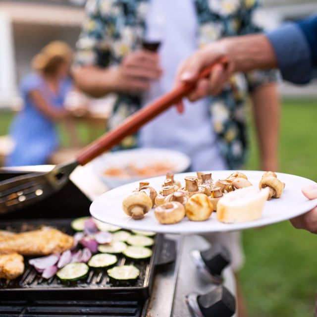 midsection of family outdoors on garden barbecue, grilling