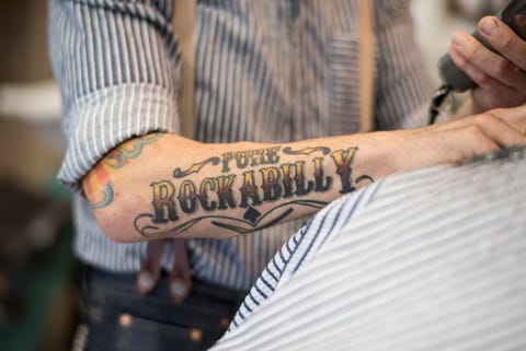 midsection of hairdresser giving haircut to customer at barber shop