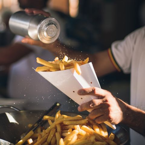 Midsection Of Man Dusting Salt On French Fries