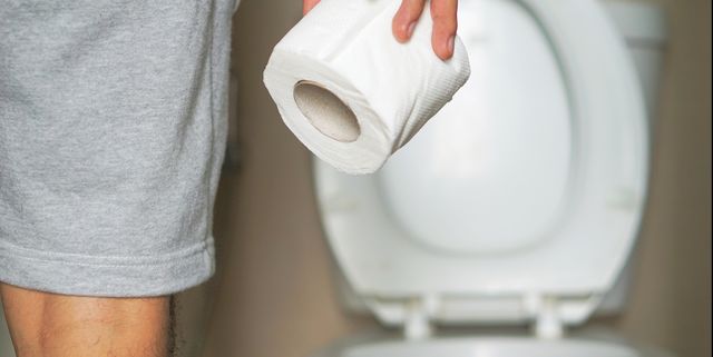 midsection of man holding toilet paper while standing in bathroom