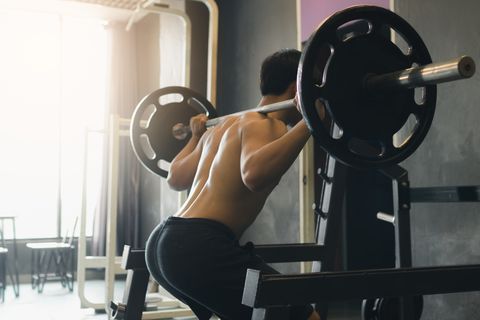 Midsection Of Man Squatting In Gym