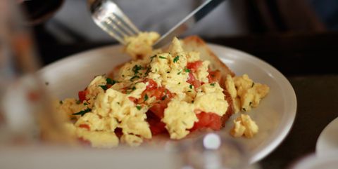 Midsection Of Person Having Scrambled Eggs In Plate On Table