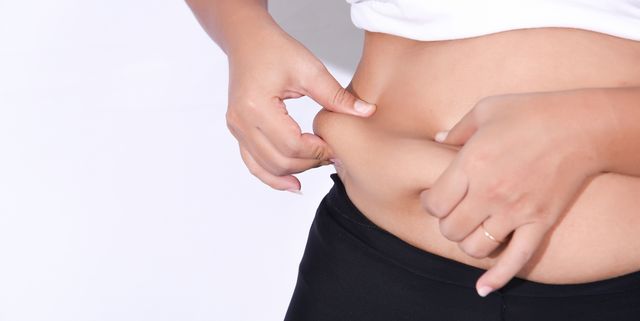 midsection of woman holding belly while standing against white background
