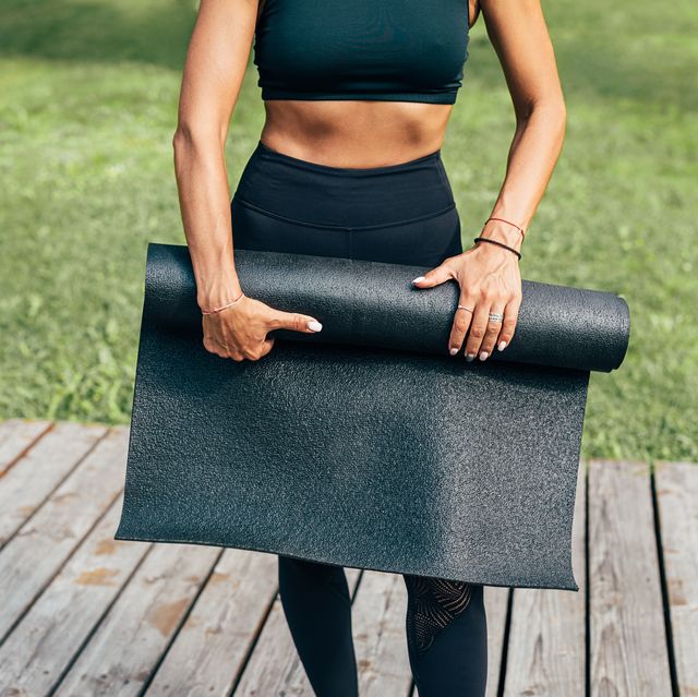 Midsection Of Woman Holding Exercise Mat While Standing Outdoors