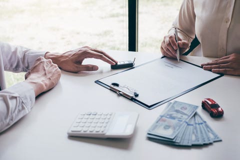 Midsection Of Woman Signing Document While Sitting With Agent In Office