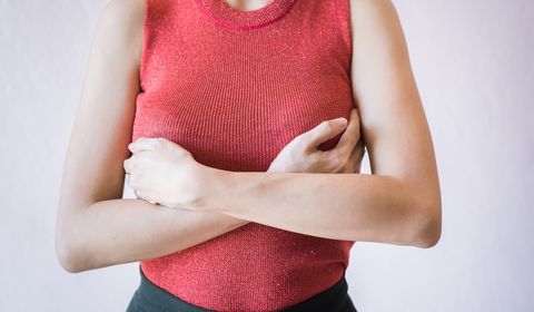 midsection of woman touching breast while suffering from cancer while standing against white background