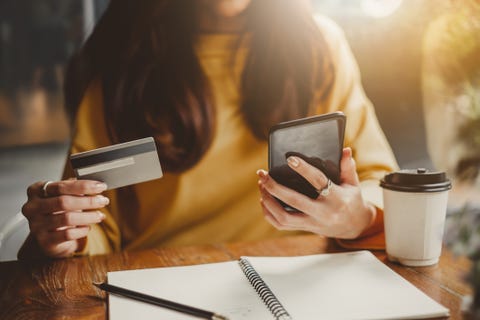 midsection of woman using mobile phone on table at cafe