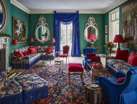 a living room with green walls and floral furniture and blue curtains with red accents all over