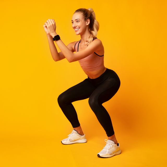 millennial girl doing deep squat exercise on yellow background