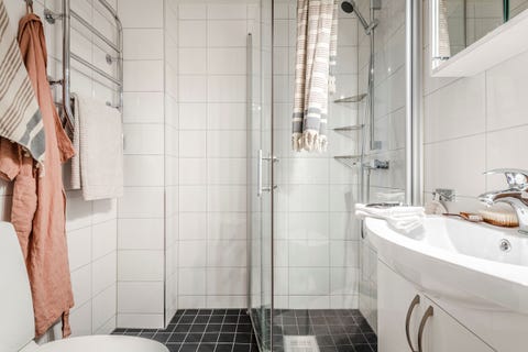 baño con ducha decorado con azulejos blancos