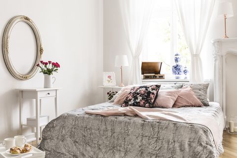 Miroir au-dessus d'un meuble blanc avec des roses à l'intérieur de la chambre avec des oreillers roses à motifs sur le lit. Vrai photo