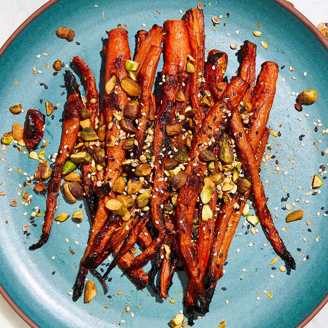 miso glazed carrots topped with pistachios and white and black sesame seeds on a teal plate